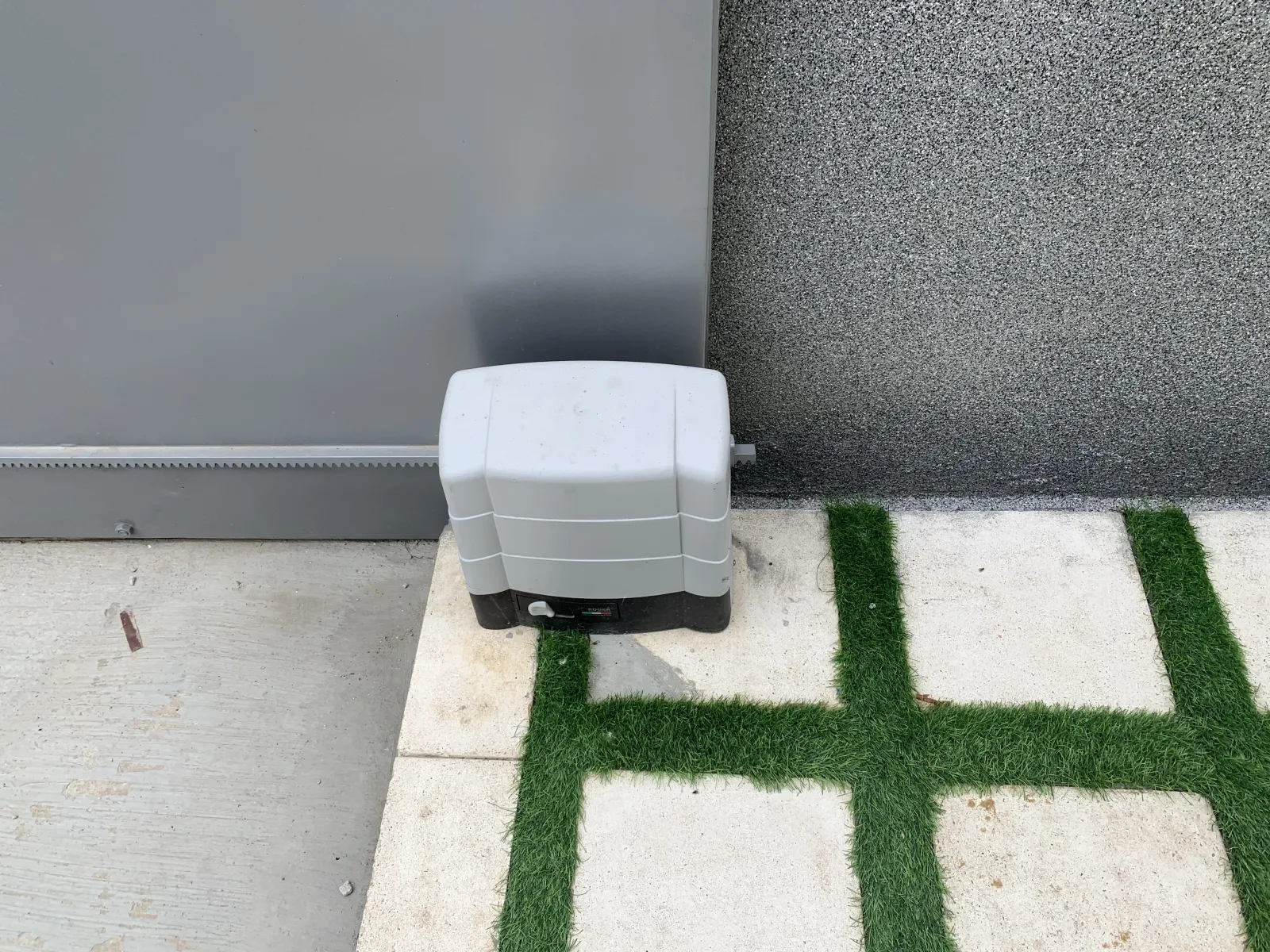 Automatismo para portão de correr, cinzento, instalado sobre pavimento junto a relva — Grupo KEFE, Luanda.