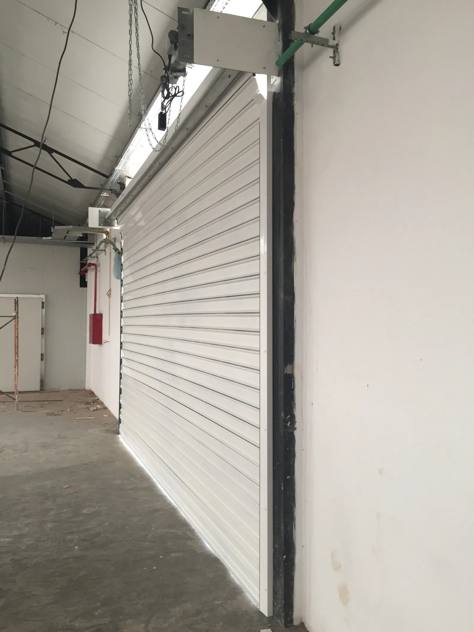 Grade de enrolar cega branca motorizada, fechada, no interior de um armazém — Grupo KEFE, Luanda.