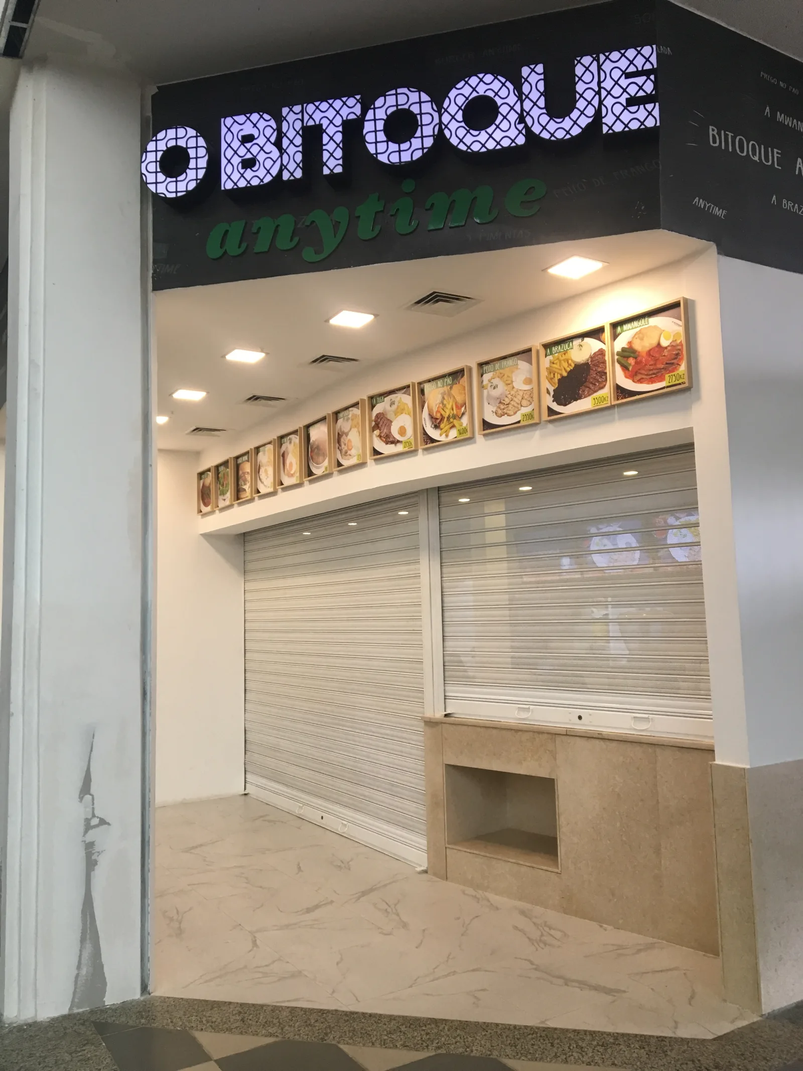 Grade de enrolar clara, semiaberta, num quiosque de restauração O Bitoque num centro comercial — Grupo KEFE, Luanda.