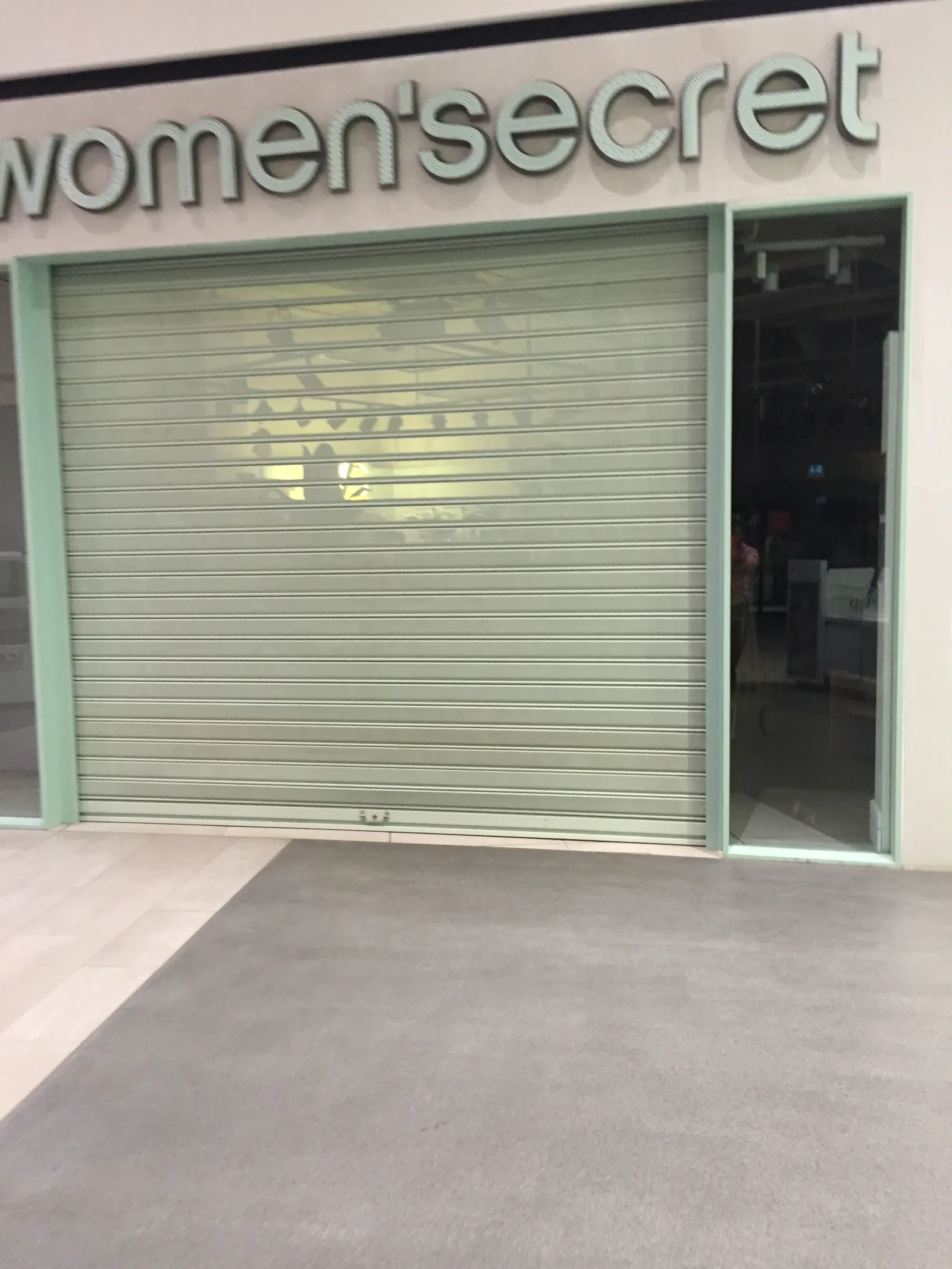 Grade de enrolar cega verde-água, fechada, numa loja de lingerie Women'secret num centro comercial — Grupo KEFE, Luanda.