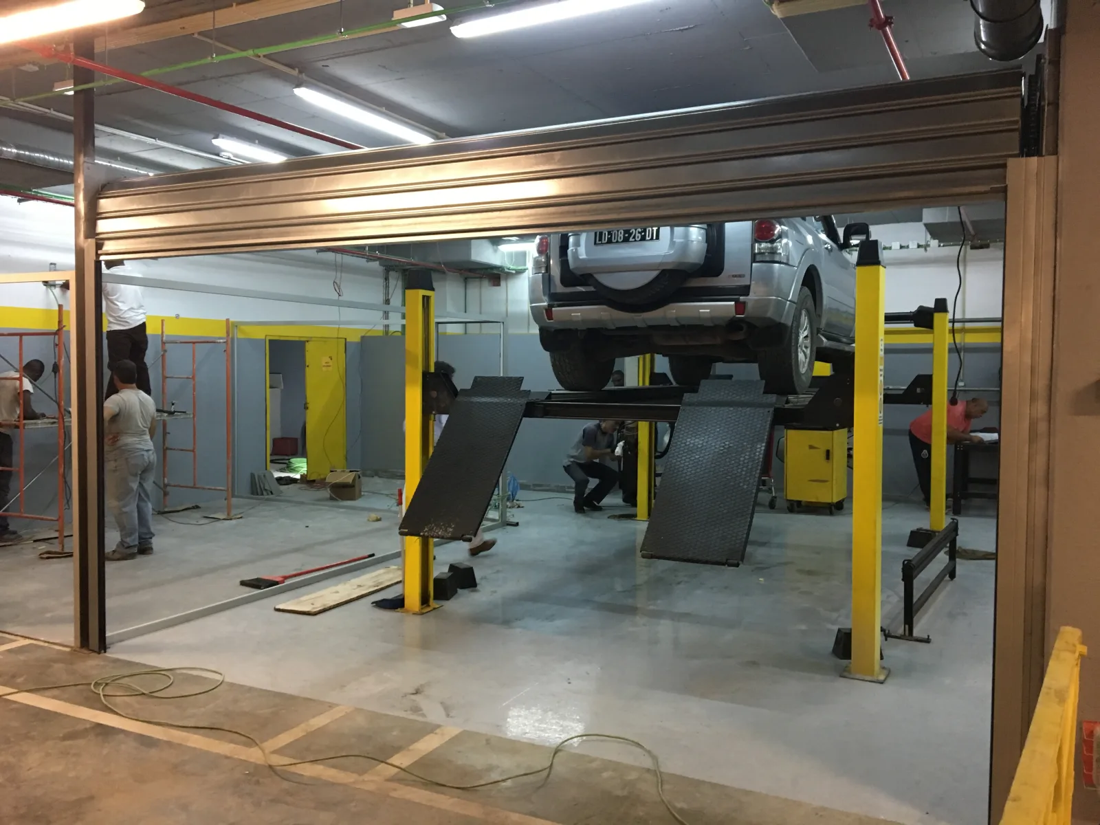 Grade de enrolar instalada numa oficina auto, com viatura no elevador — Grupo KEFE, Luanda.