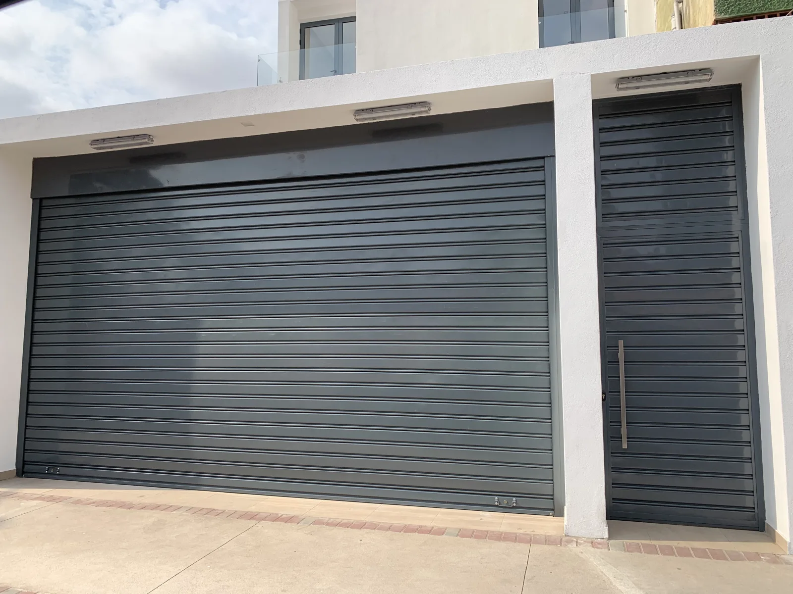 Grade de enrolar cega cinzento-antracite de garagem, com porta a condizer, numa moradia — Grupo KEFE, Luanda.