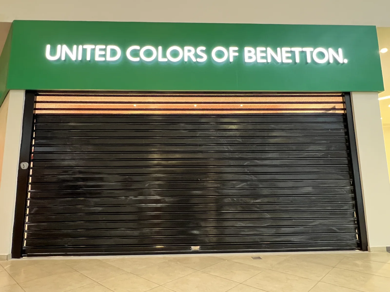 Grade de enrolar cega preta, fechada, numa loja United Colors of Benetton num centro comercial — Grupo KEFE, Luanda.