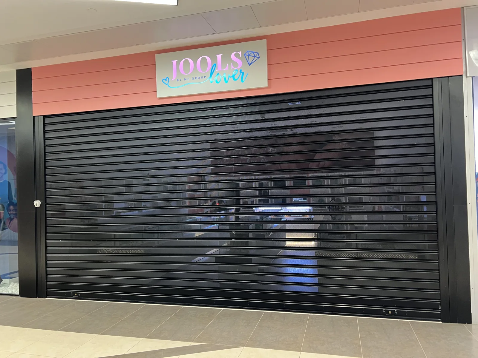 Grade de enrolar micro-perfurada preta numa loja de acessórios Jools Fever num centro comercial — Grupo KEFE, Luanda.