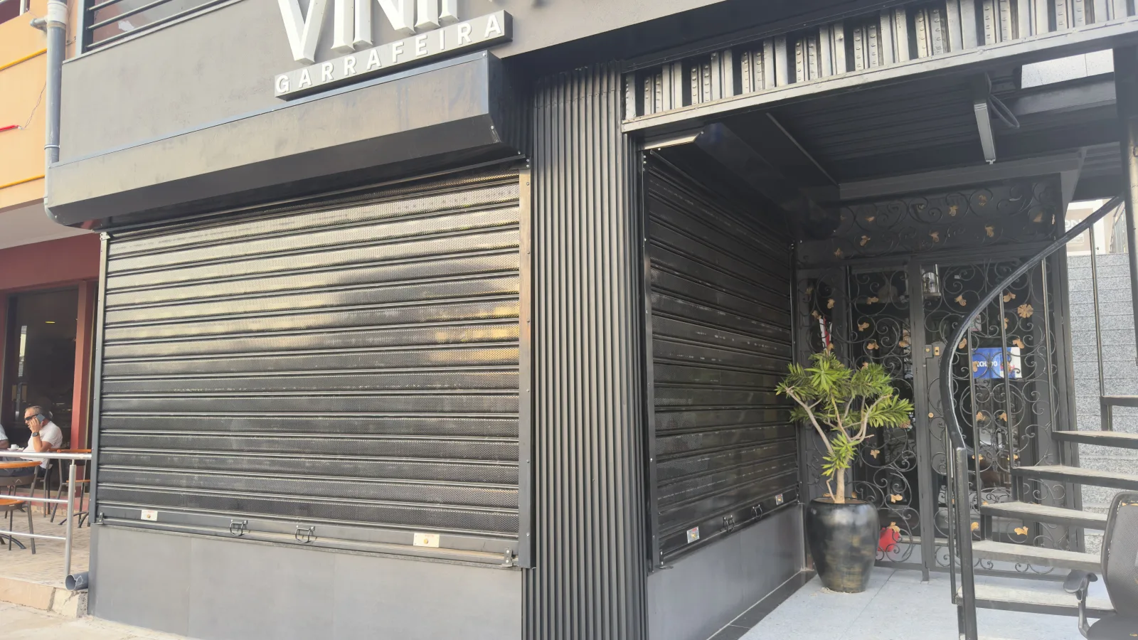 Grade de enrolar cega escura na fachada de rua de um restaurante — Grupo KEFE, Luanda.