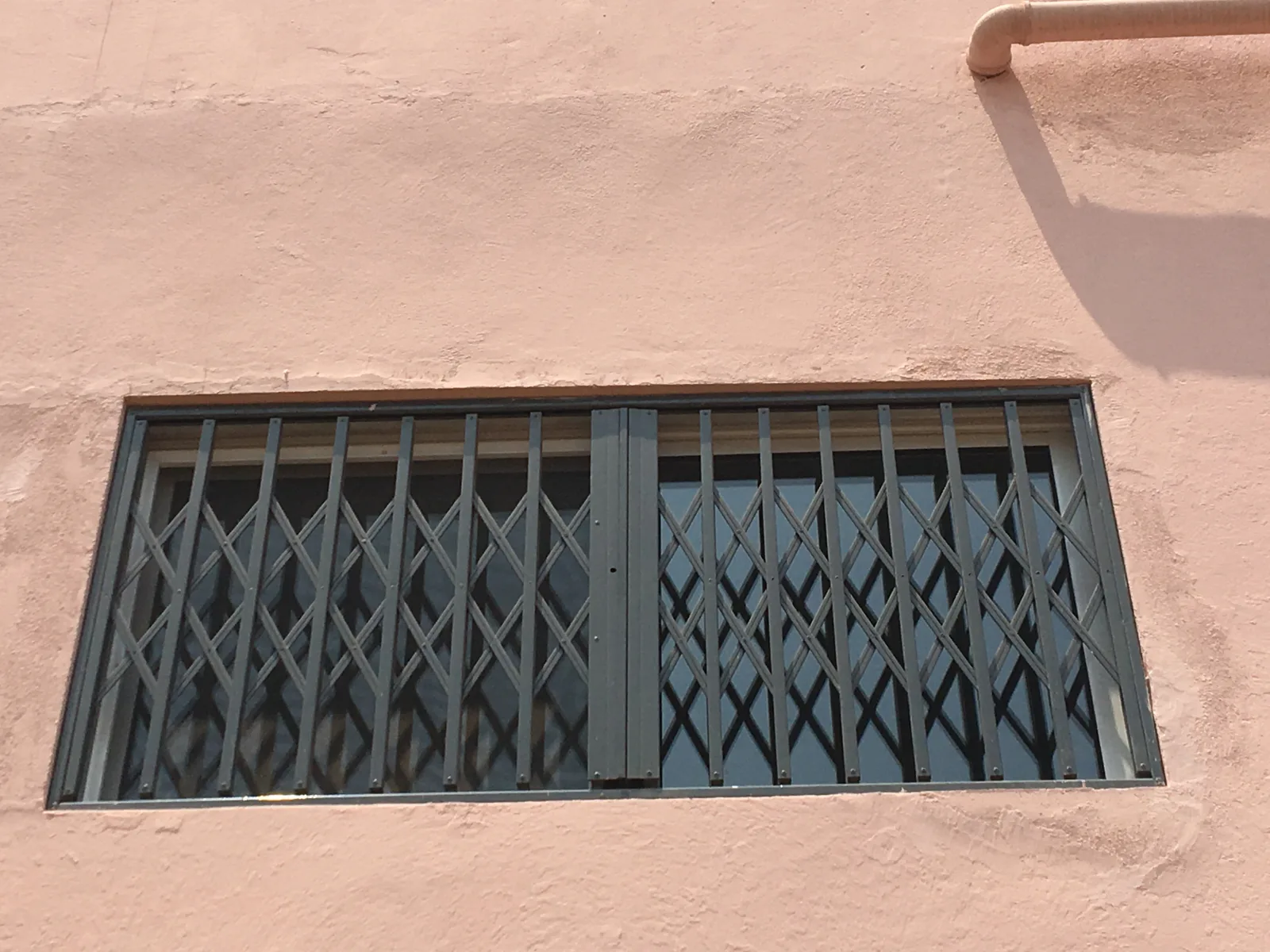 Grade lagarto extensível a proteger uma janela na fachada de um edifício — Grupo KEFE, Luanda.