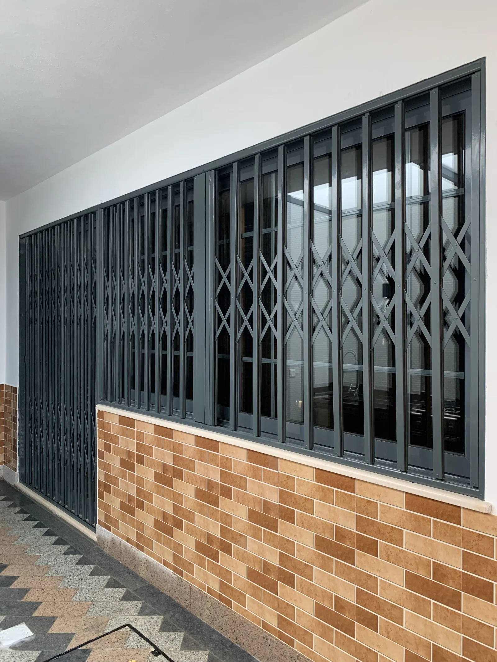 Grade lagarto cinzento-antracite extensível a proteger uma montra envidraçada — Grupo KEFE, Luanda.