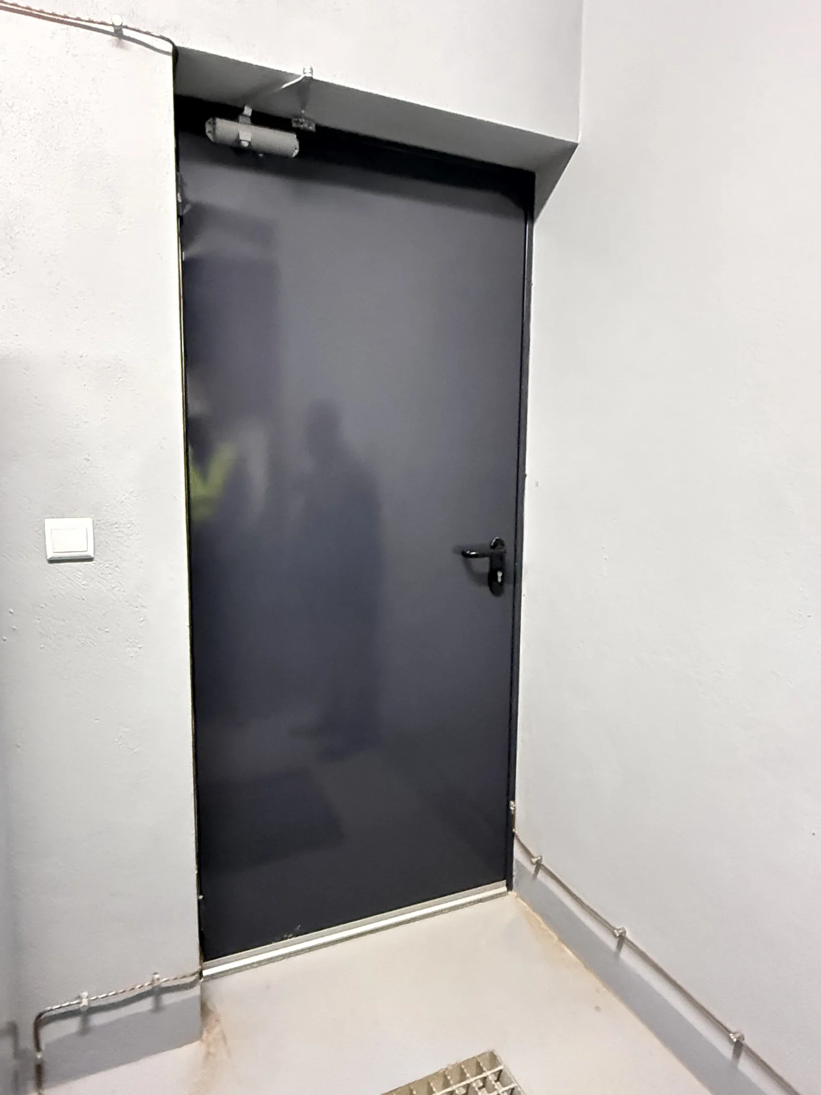 Porta corta-fogo escura de uma folha com mola de fecho automático, numa casa de máquinas — Grupo KEFE, Luanda.