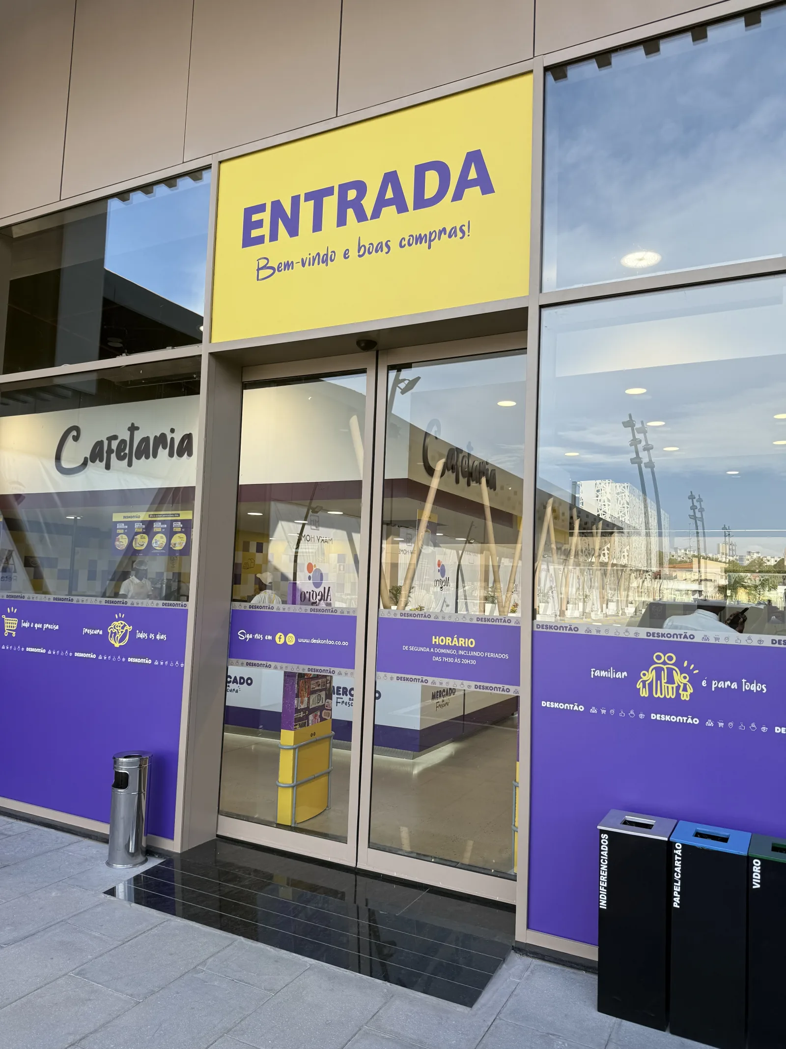 Porta automática de vidro na entrada do supermercado Deskontão, junto à cafetaria — Grupo KEFE, Luanda.