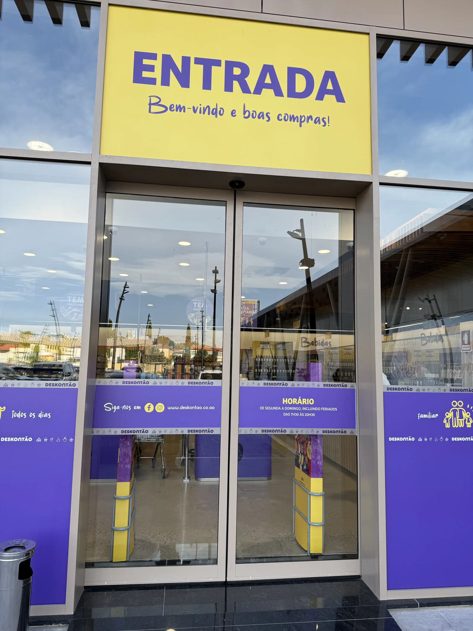 Portas automáticas de vidro na entrada do supermercado Deskontão, sob o letreiro "Entrada" — Grupo KEFE, Luanda.