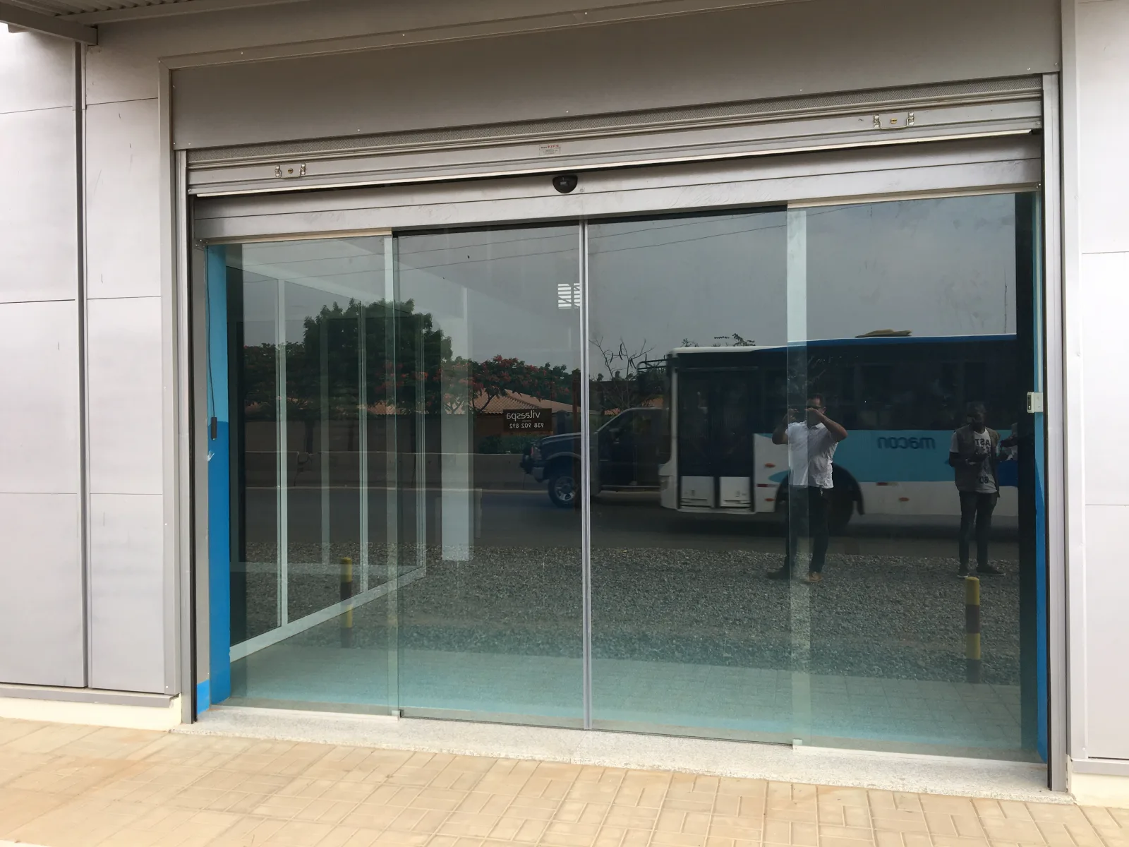 Porta automática de vidro corrediça à entrada de um edifício comercial — Grupo KEFE, Luanda.