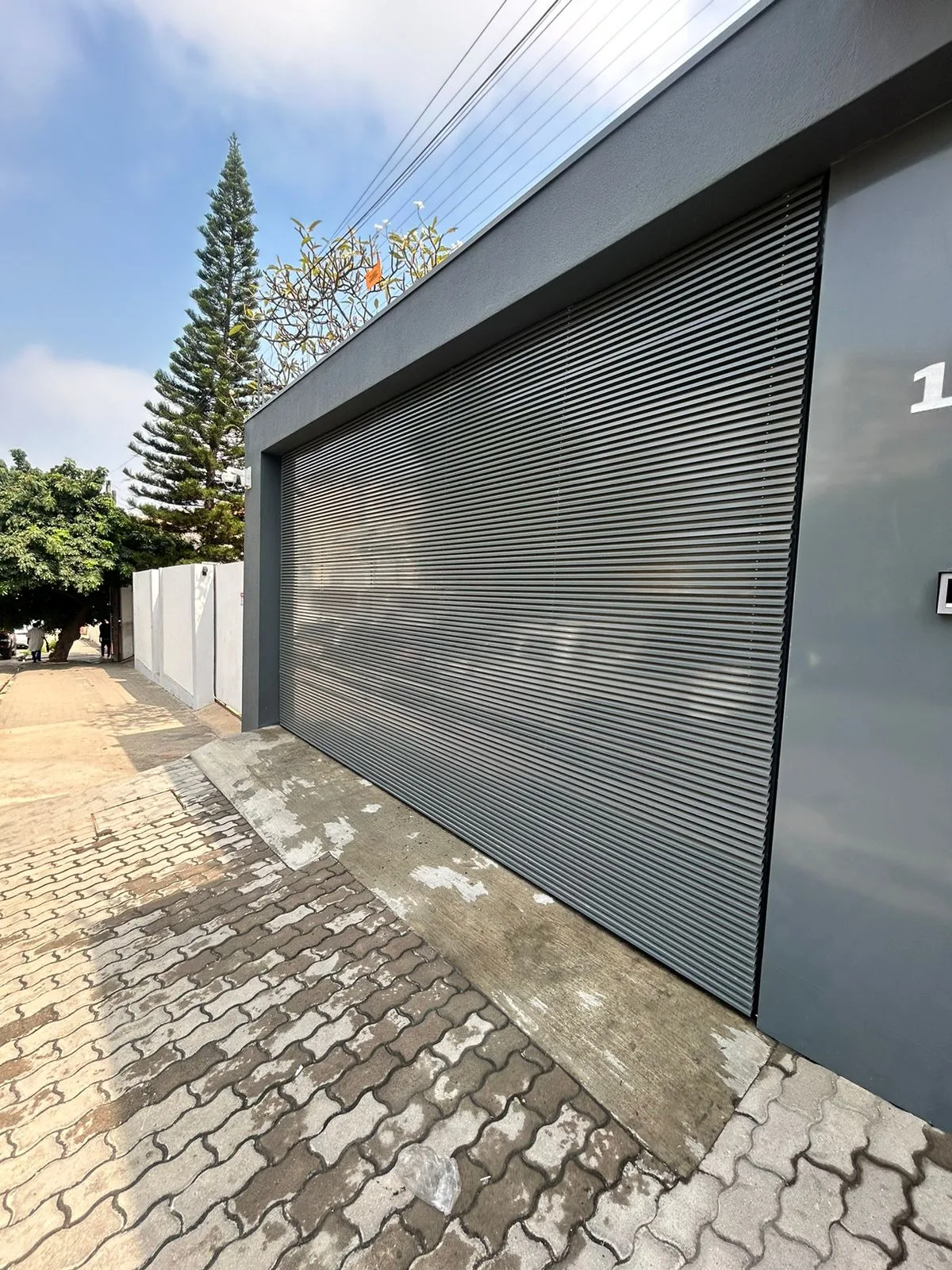 Portão de lâminas metálicas cinzento-escuro na garagem de uma moradia