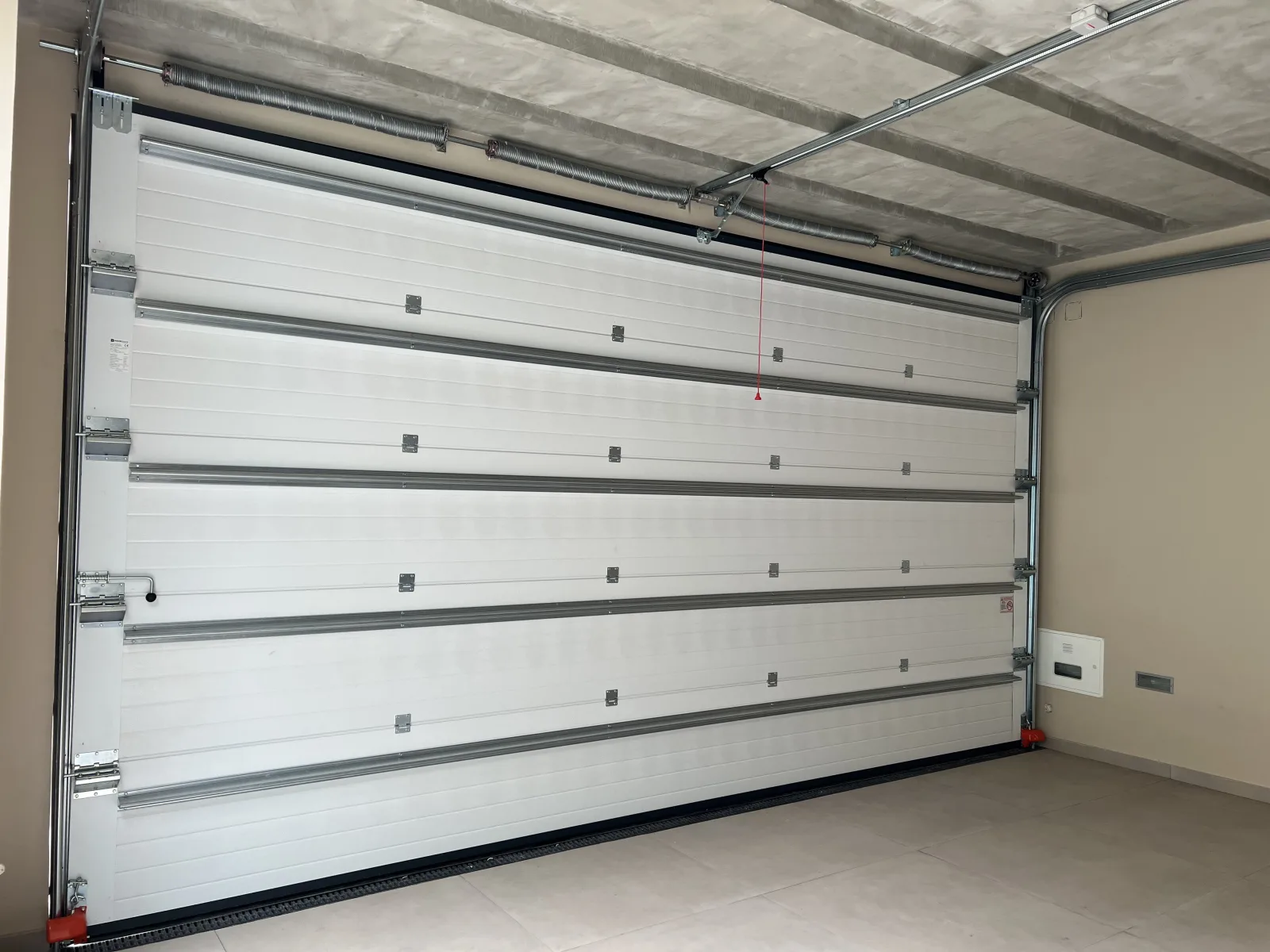 Portão seccionado branco com perfis de reforço horizontais numa garagem