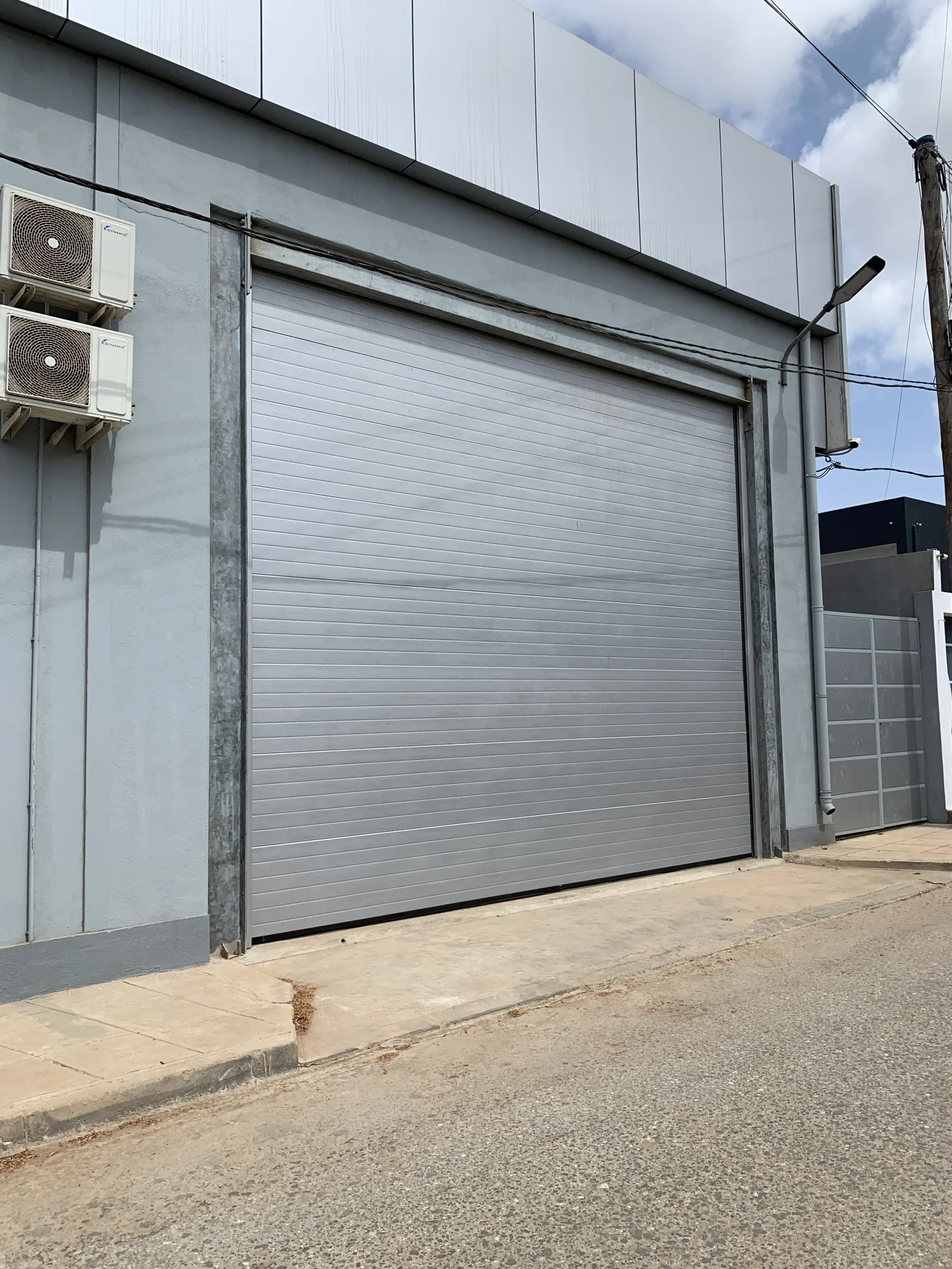 Portão seccionado cinzento de painéis frisados na fachada de um armazém