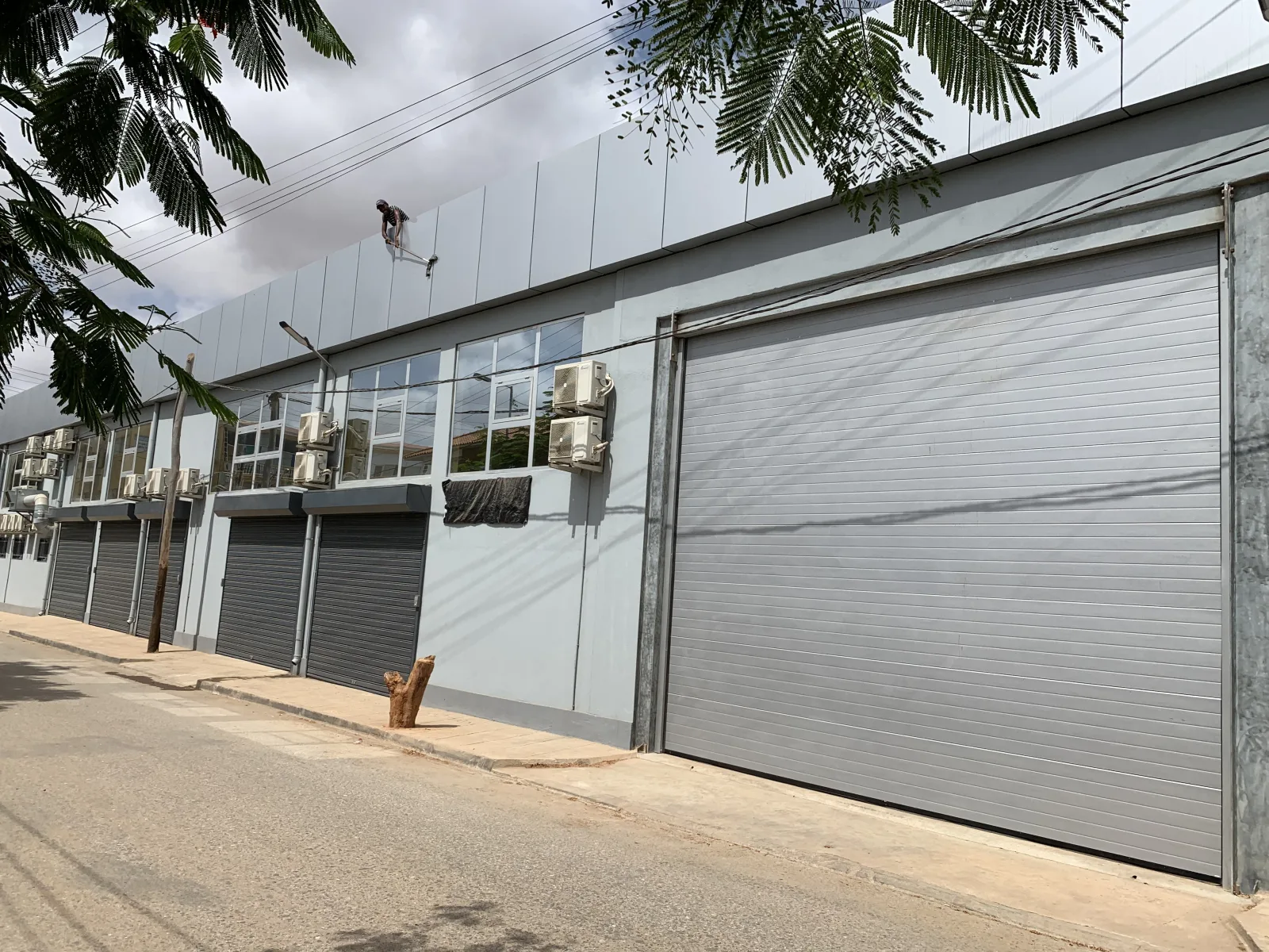 Grande portão seccionado cinzento de painéis frisados na fachada de um armazém