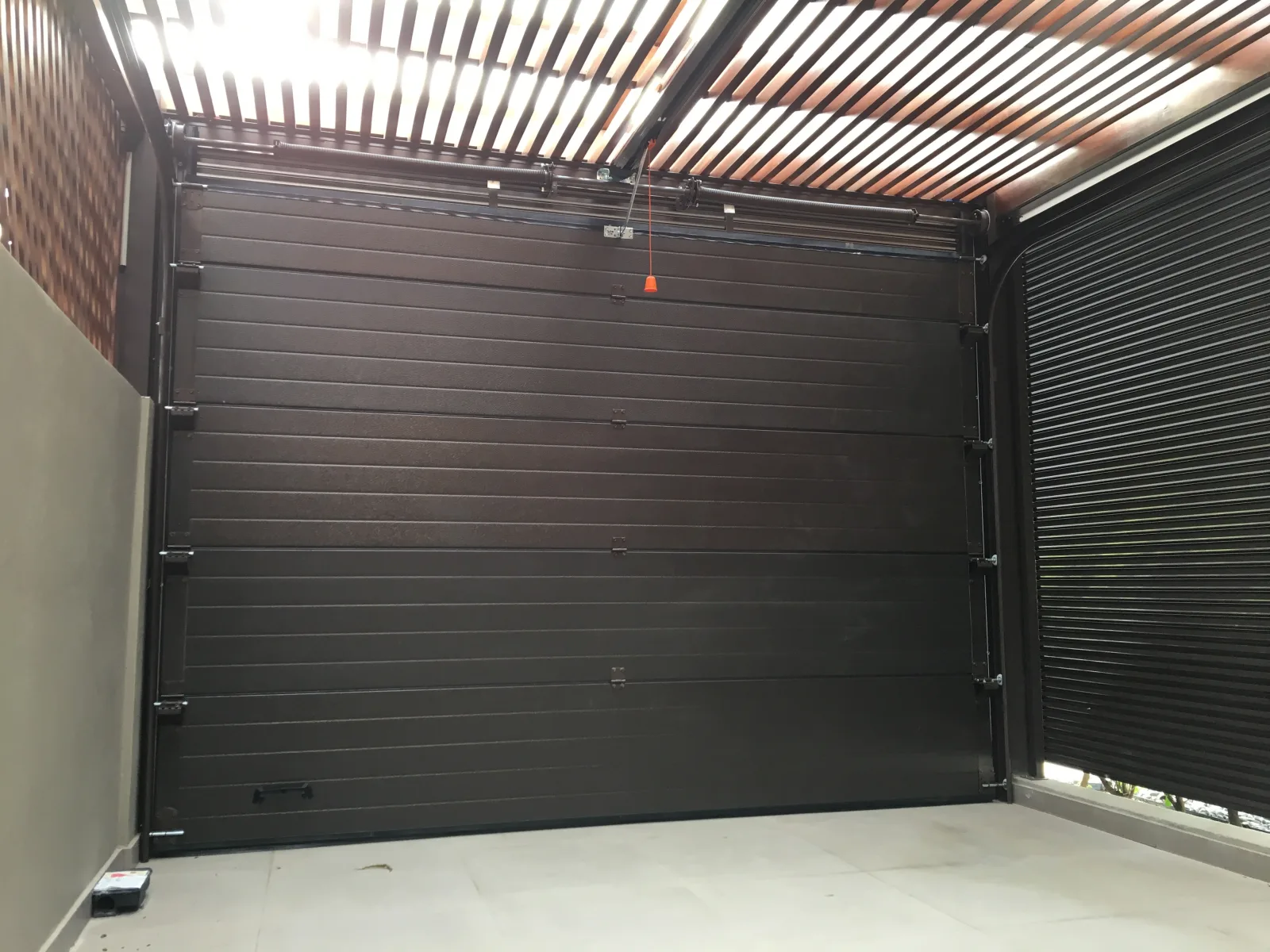 Portão seccionado castanho-escuro visto do interior da garagem
