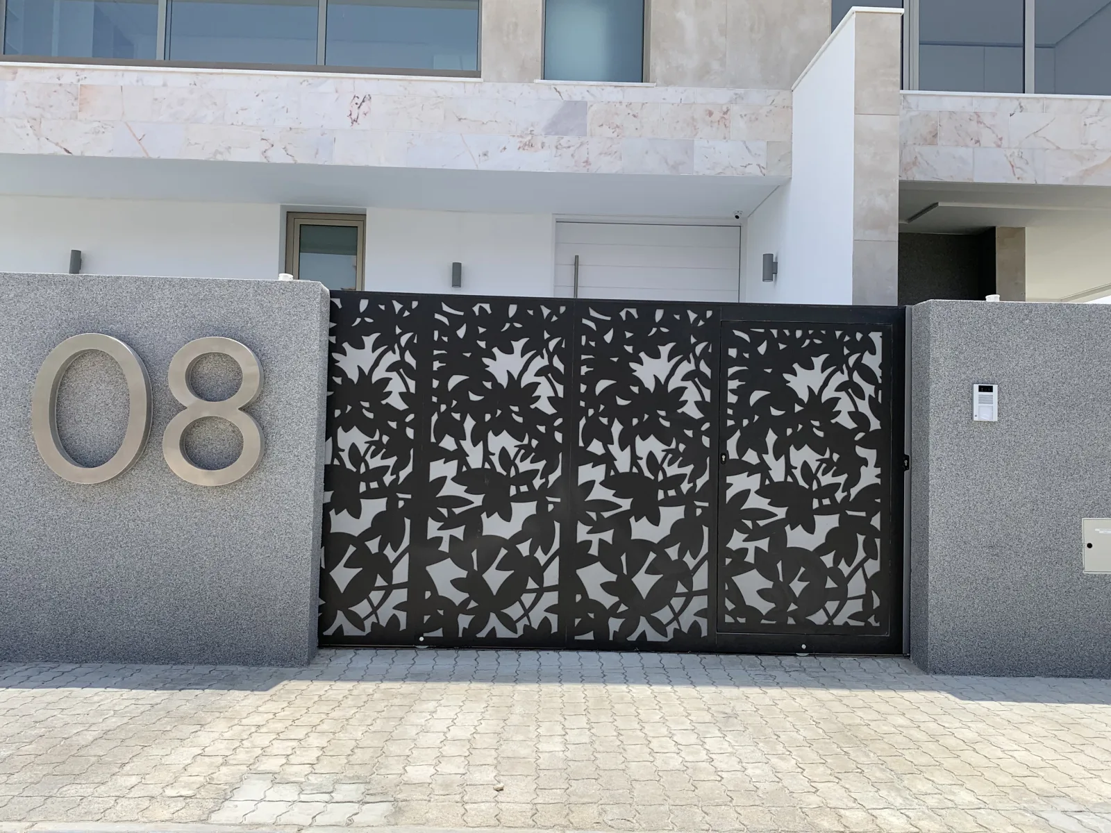 Portão decorativo em chapa metálica recortada a laser com padrão floral, preto, à entrada de uma moradia — Grupo KEFE, Luanda.