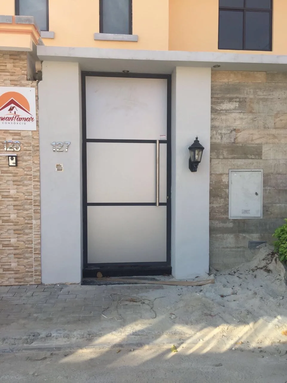 Porta de entrada pedonal em estrutura metálica com vidro fosco, numa moradia — Grupo KEFE, Luanda.