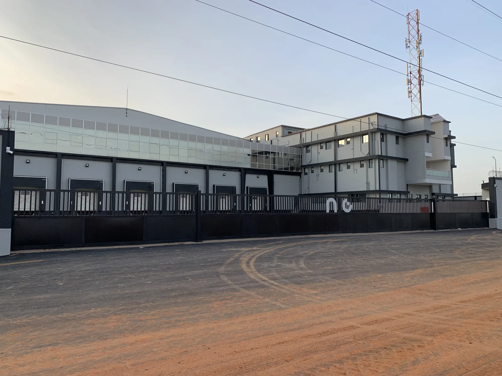 Vedação e portões metálicos escuros ao longo de um complexo industrial — Grupo KEFE, Luanda.